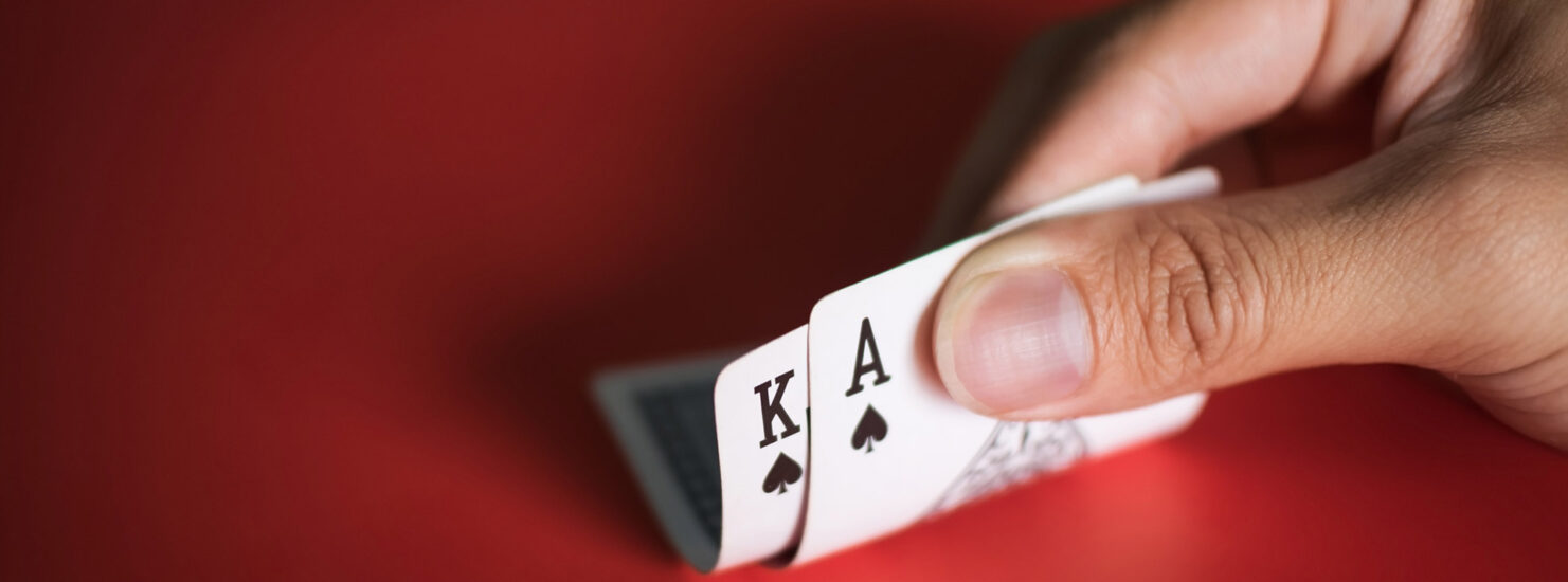 Blackjack cards in hands on red table